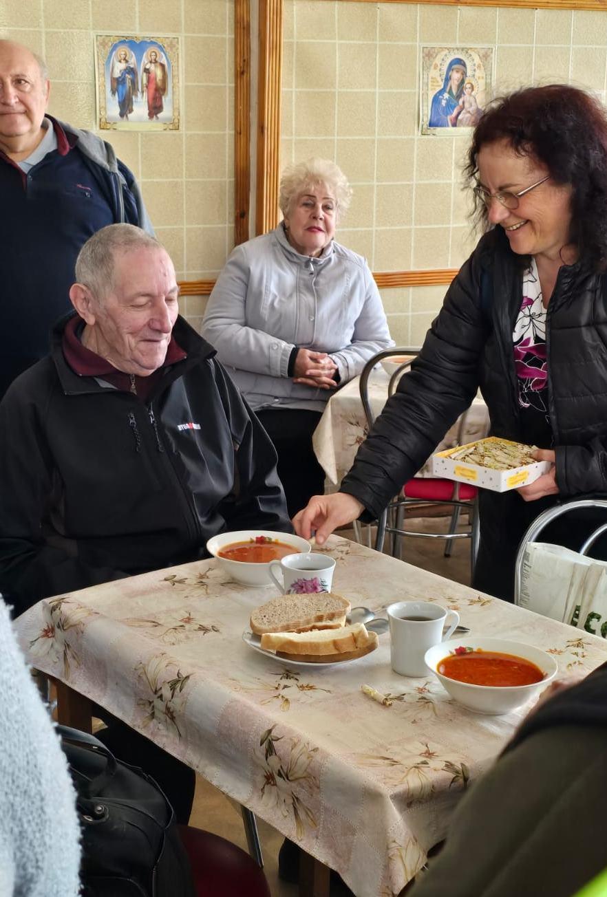 Helferin serviert Essen an einem gedeckten Tisch